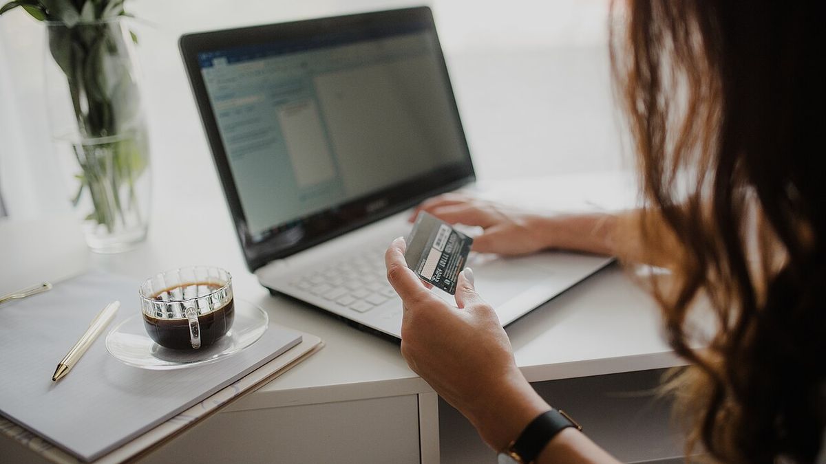 A woman at a laptop holding a payment card to set up online banking