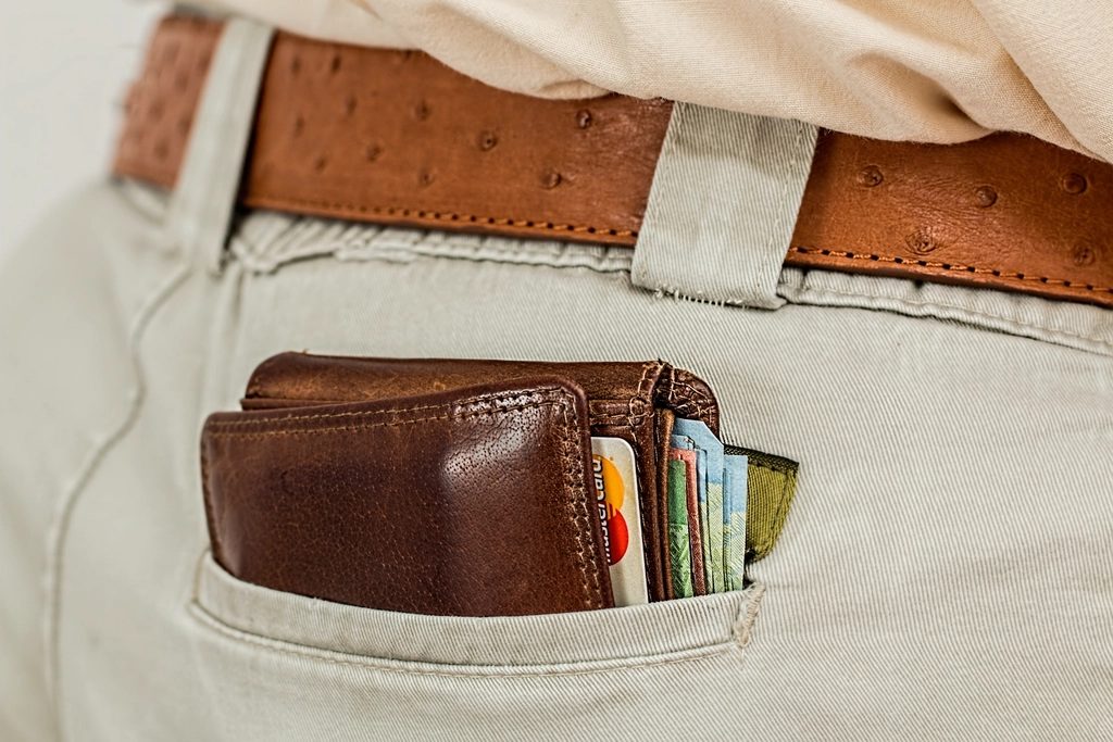 A wallet in a back pocket with a payment card and colorful euro banknotes tucked inside